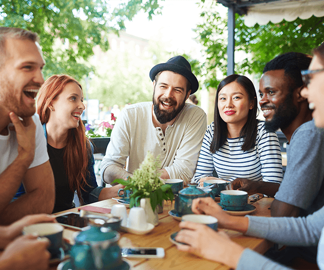 A group of friends sitting around a table laughing.