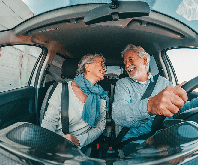 Happy older couple smiling in their car.