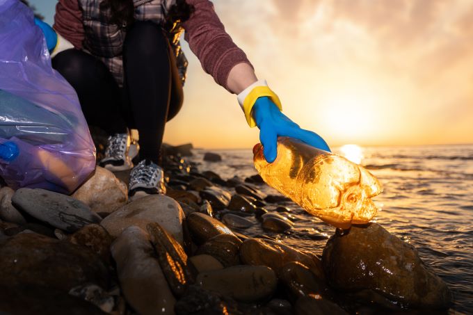 A woman picks up trash out of the ocean