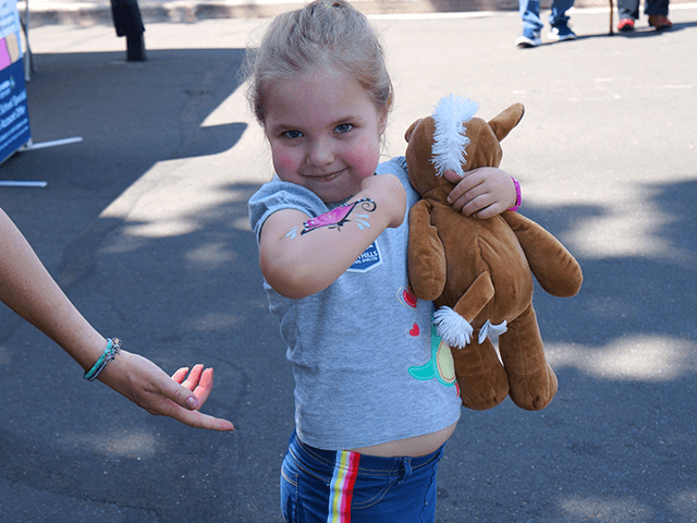 Close-up of a smiling girl with stuffed animal and painted arm