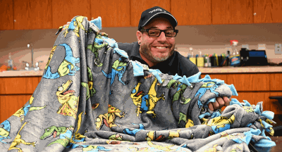 Volunteer holding up completed no sew blanket