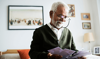 Elderly man with glasses reviewing some mail