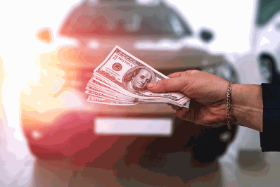 Hundred dollar bills in front of a new vehicle