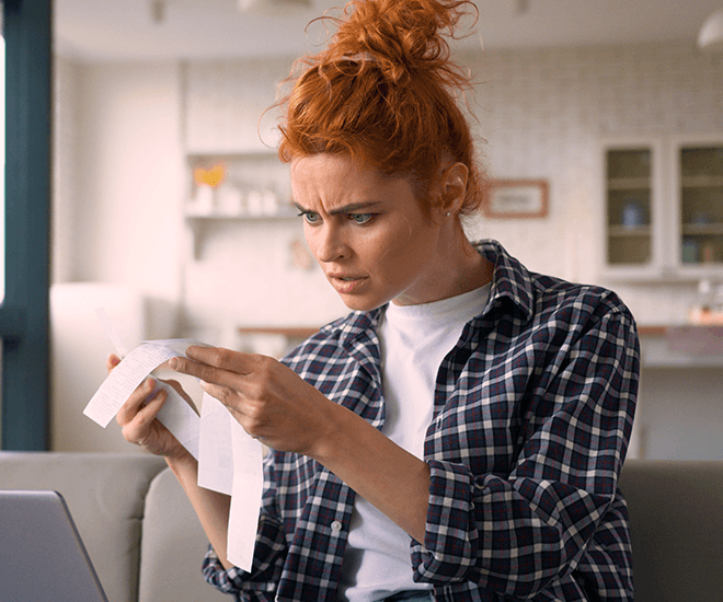 Confused woman looking at a receipt.