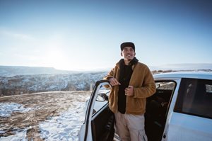 Man standing by car on mountaintop