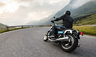 Person riding on their motorcycle on a curvy mountain road.