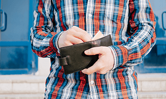 Man wearing a plaid shirt reaching into his wallet