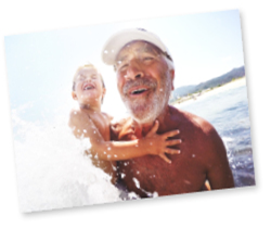 Happy man in the water on the beach with his grandson