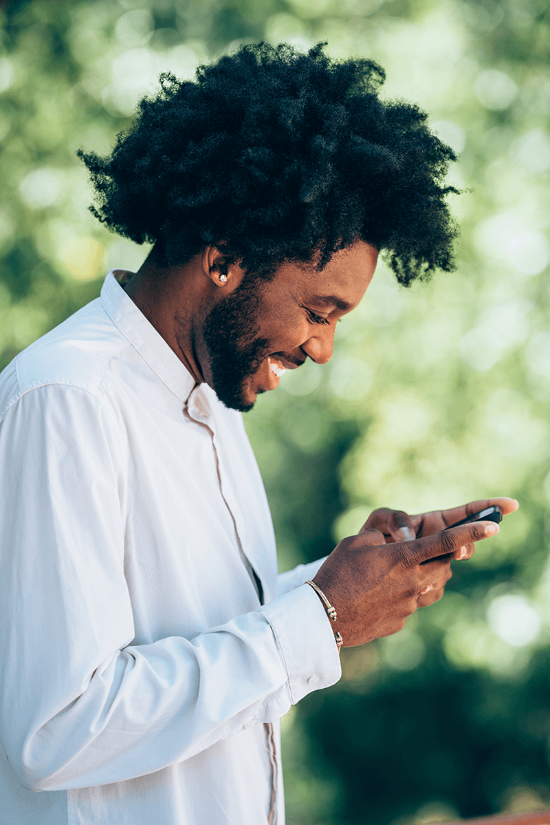 Happy African-American man smiling at his phone.
