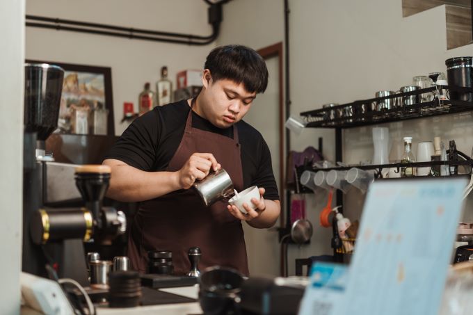 Barista pouring milk in coffee