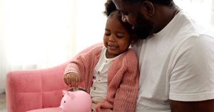 father and daughter save money in piggy bank