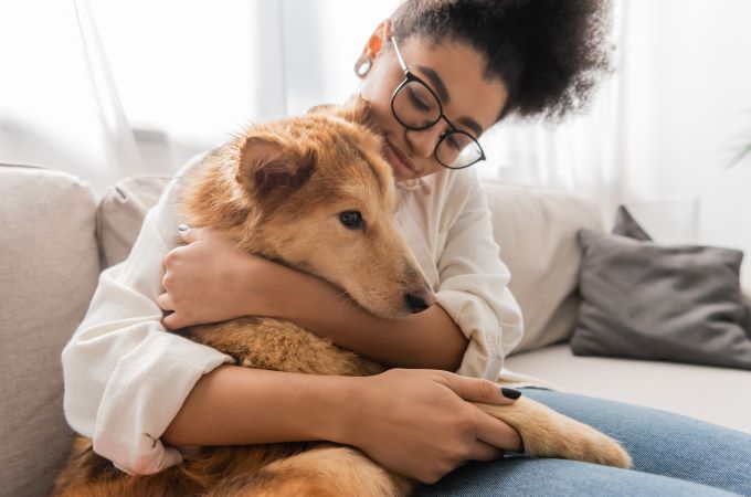 woman cuddling dog on couch