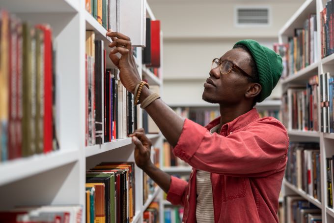Male student looking for book in library