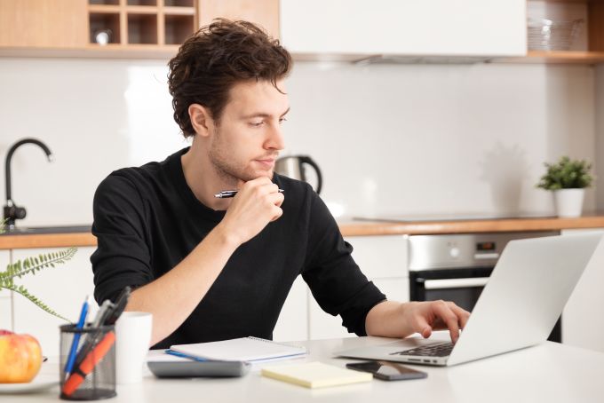 young man paying bills on laptop