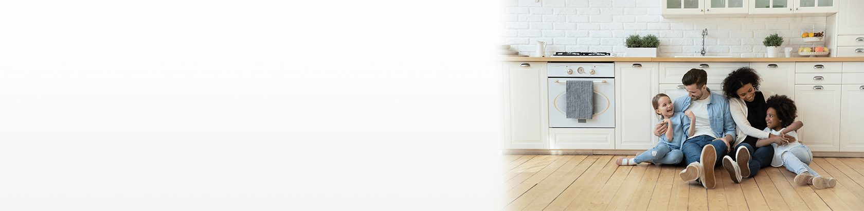 A happy family sitting on their new kitchen floor together.