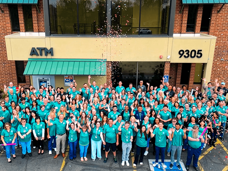 Credit Union of Denver employees celebrating with confetti in front of a branch building.